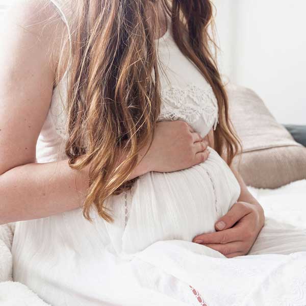 Close up image of a woman holding her pregnant belly